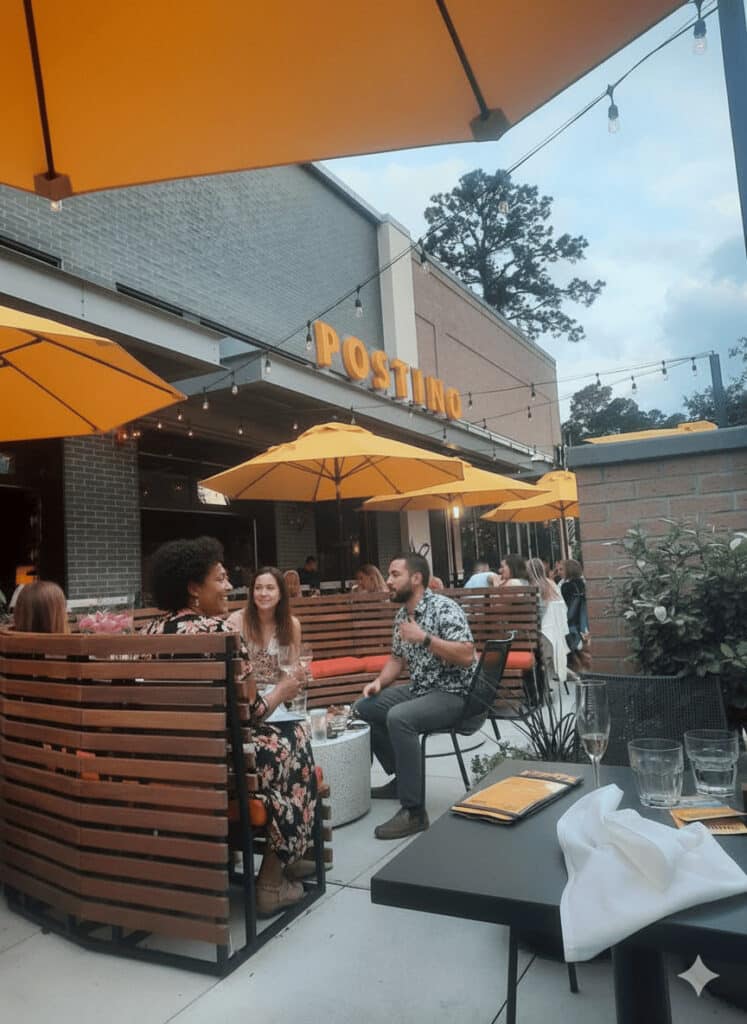 Terraza al aire libre de Postino Woodlands en Hughes Landing, The Woodlands TX. Amigos disfrutando de vinos y bruschettas en el patio pet-friendly.